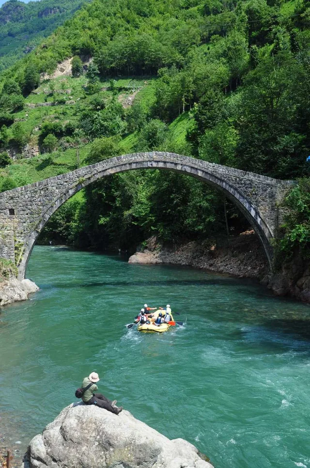 Tarihi taş köprünün altında rafting yapan bir grup
